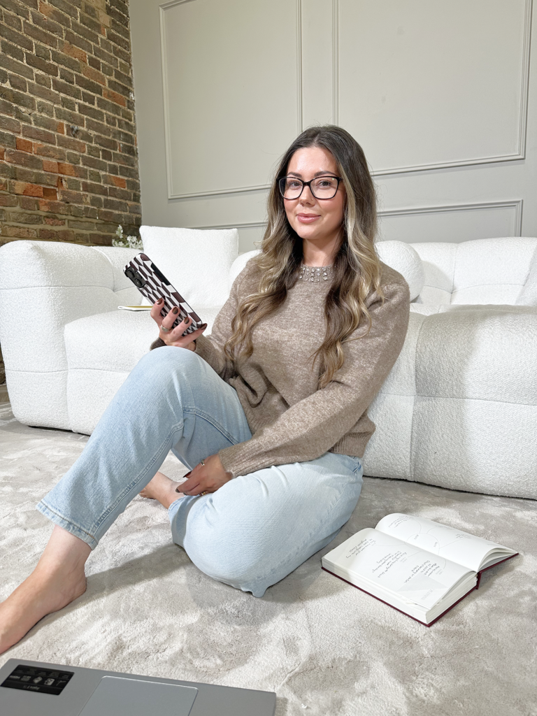 Zaara King sitting with her phone and notebook, building her beauty business and planning growth strategies for beauty professionals.